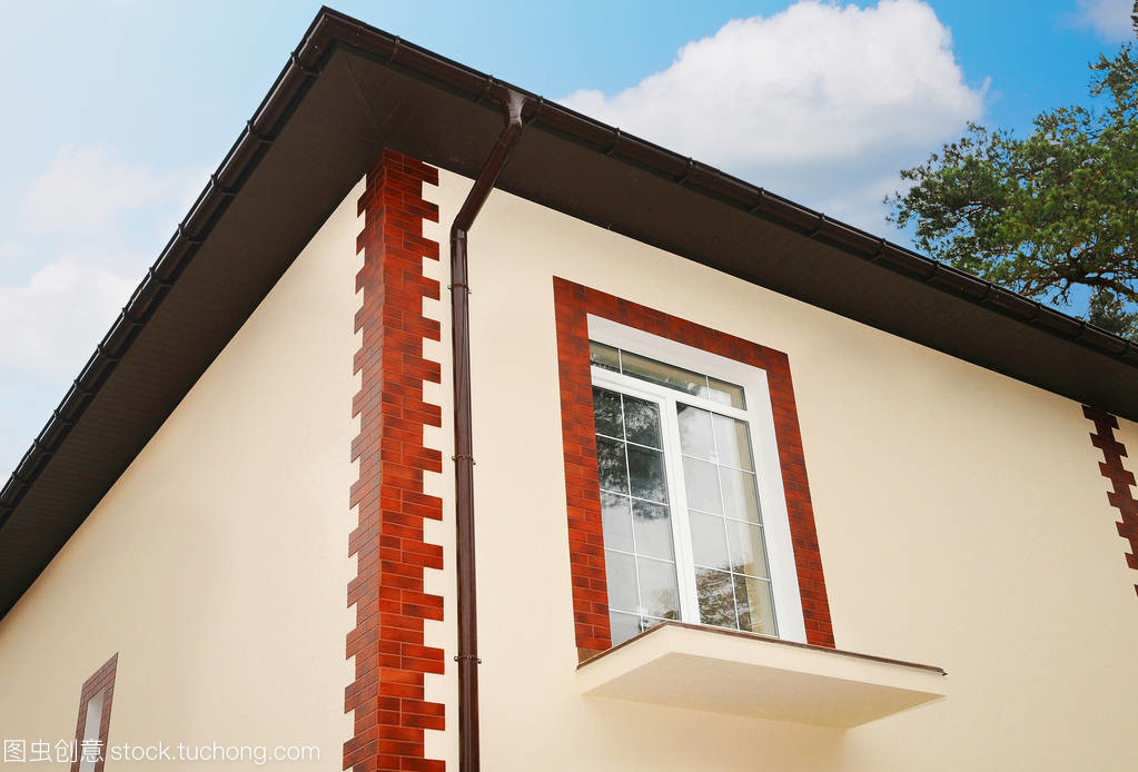 在一所新房子的新窗口。未完成的陽臺。裝飾石膏。裝飾瓷磚。屋面工程施工。城市房屋或建筑物,門面模式。雨裝訂線