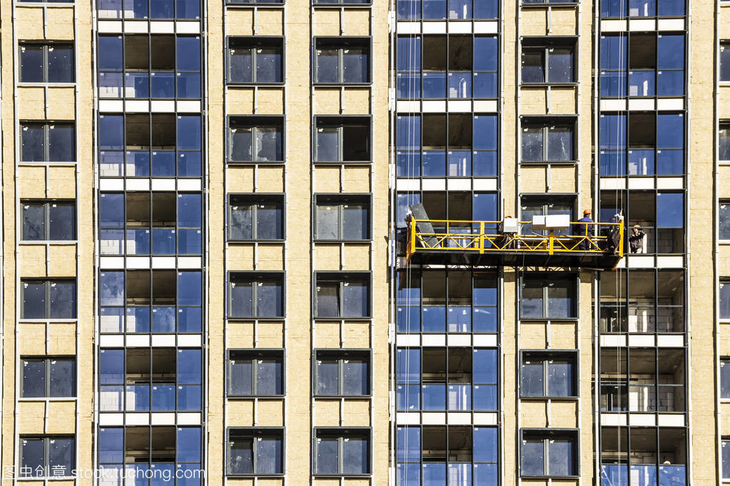 建筑裝飾工程的建設者在新住宅樓宇和塔式起重機的建設搖籃的立面